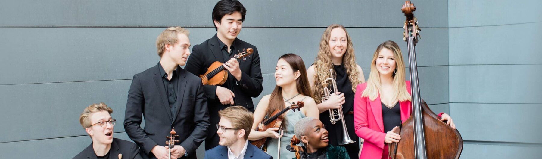 Conservatory students standing next to Thayer Hall with instruments